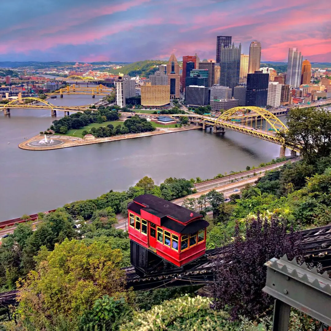 A red and black train on tracks near water.